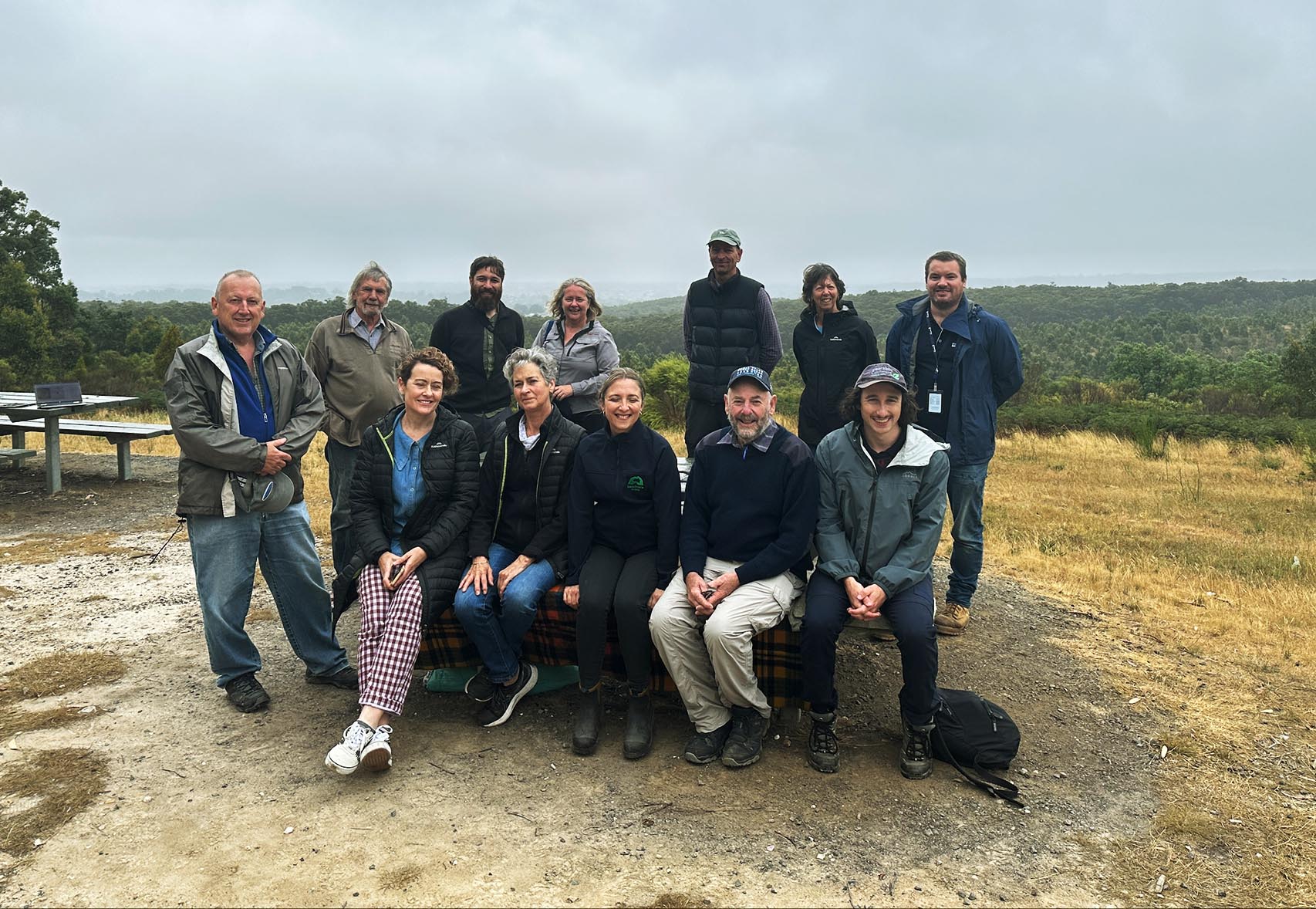 A group of twelve people pose for the camera on a hilltop