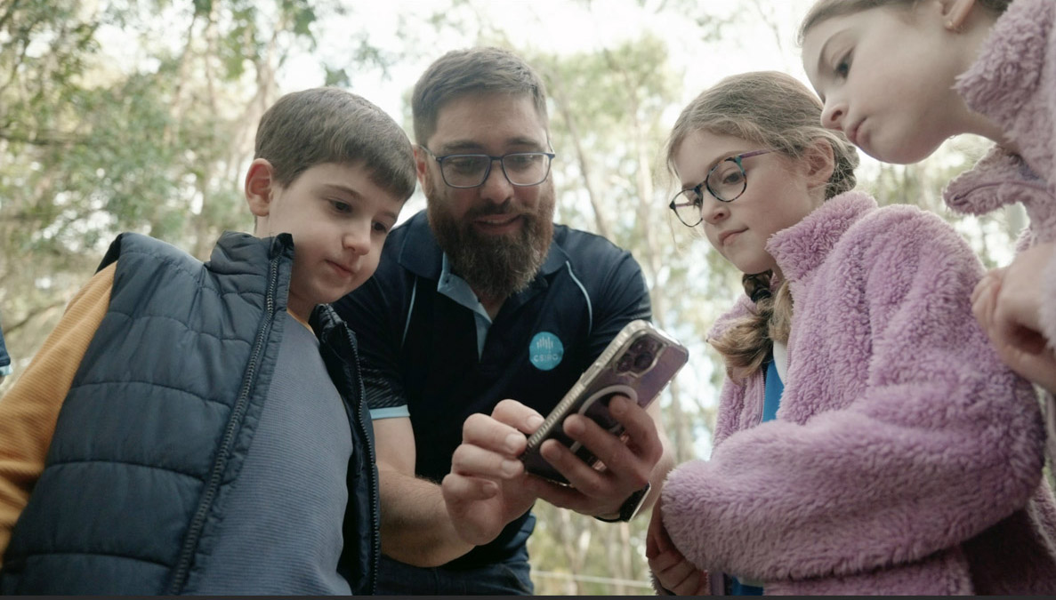 Three children watch as Dr Hoskins uses a phone